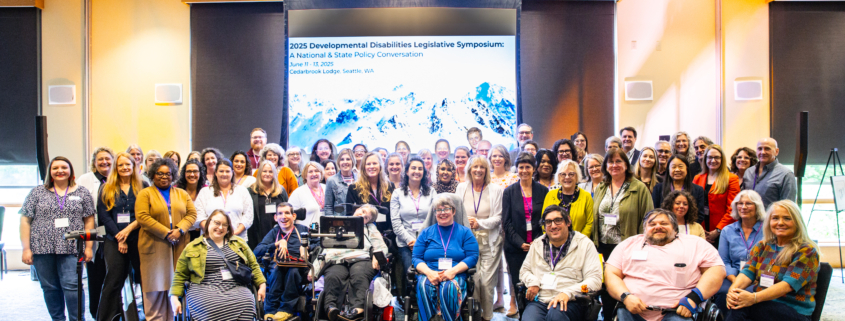 A group of approximately 50 adults gathered for a group photo and smiling at the camera